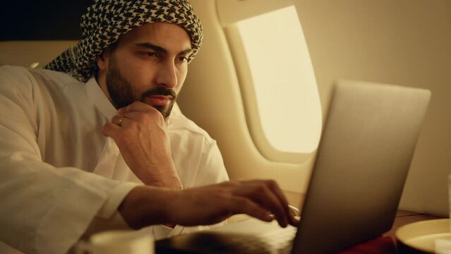 Thoughtful muslim working laptop on business trip closeup. Rich man typing