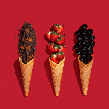 Wafer ice cream cones with fresh fruits strawberry ,cherry and chocolate ,continuous pattern on red background. Isolate top view, hard light