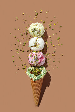 Wafer ice cream cone with ice cream balls pistachio, raspberry,vanilla and banana ,isolated on brown background. Continous pattern. top view, hard light