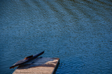 Canoe placed at the edge of the lake dock with paddle next to it