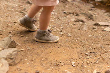 Children's feet in shoes on the shore of a pond.