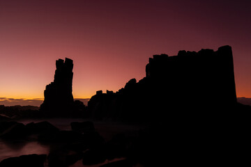 Obraz premium Silhouette of rock formation on the shore.