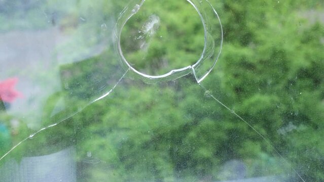 4k video of broken glass in the window frame, close-up, hole in the glass