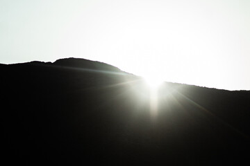 Sol escondiéndose detrás de un pequeño monte en el desierto. 