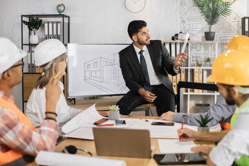 Group of international architects, designers and engineers sitting at office and working on common...