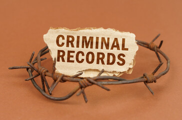 On a brown surface, barbed wire and a cardboard sign with the inscription - Criminal records
