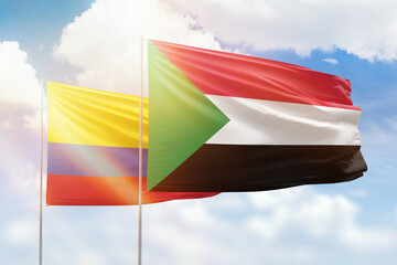 Sunny blue sky and flags of sudan and colombia