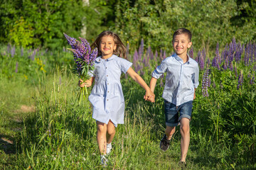 Smiling boy and a girl run across the field holding hands.