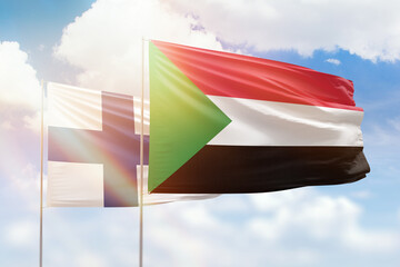 Sunny blue sky and flags of sudan and finland