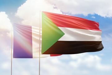Sunny blue sky and flags of sudan and france
