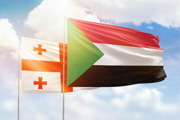 Sunny blue sky and flags of sudan and georgia