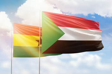 Sunny blue sky and flags of sudan and ghana