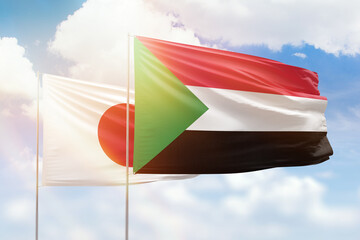 Sunny blue sky and flags of sudan and japan