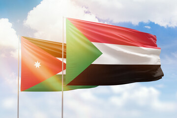 Sunny blue sky and flags of sudan and jordan