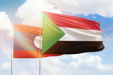 Sunny blue sky and flags of sudan and laos