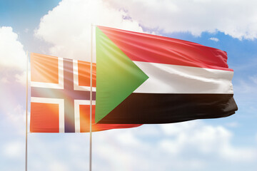 Sunny blue sky and flags of sudan and norway