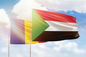 Sunny blue sky and flags of sudan and romania