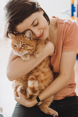 Attractive woman embracing her pet with smile, playing with cat. Attractive beautiful girl.