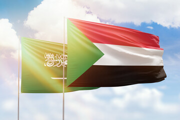 Sunny blue sky and flags of sudan and saudi arabia