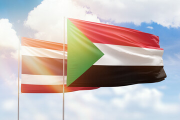 Sunny blue sky and flags of sudan and thailand