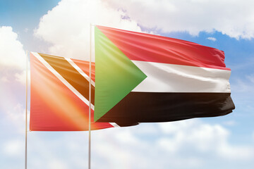 Sunny blue sky and flags of sudan and trinidad and tobago