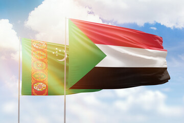 Sunny blue sky and flags of sudan and turkmenistan
