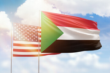 Sunny blue sky and flags of sudan and usa