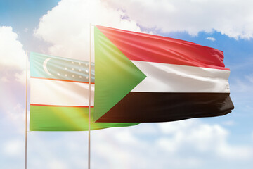 Sunny blue sky and flags of sudan and uzbekistan
