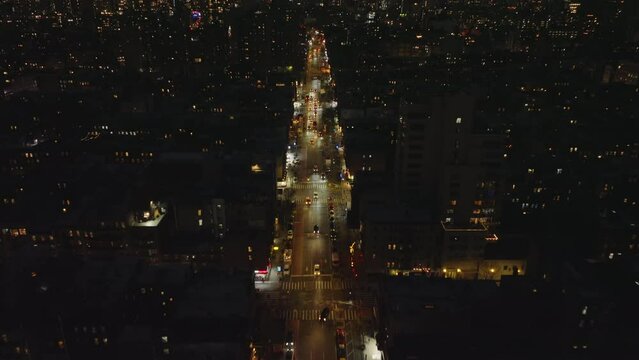 High Angle View Of Night City. Forwards Fly Above Vehicles Driving On Multilane Straight Street Glowing Into Darkness. Manhattan, New York City, USA