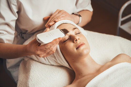 Caucasian woman receiving facial procedure of cleansing the skin with ultrasound scrubber. Facial treatment. Skin care. Beauty skin.