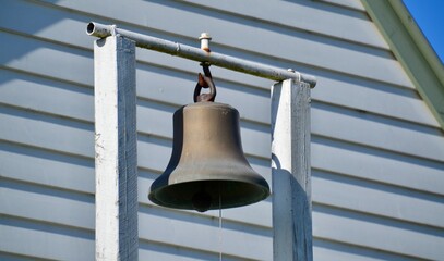 Brass bell outside an old wooden church or chapel
