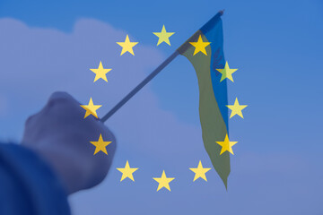 Defocus European union and Ukraine. Large national symbol fluttering in blue sky. Support and help Ukraine, Independence Constitution Day, National holiday. Hand holding flag. Candidate. Out of focus