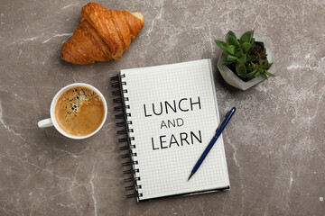 Lunch and Learn concept. Notebook, cup of aromatic coffee, delicious croissant and plant on brown...