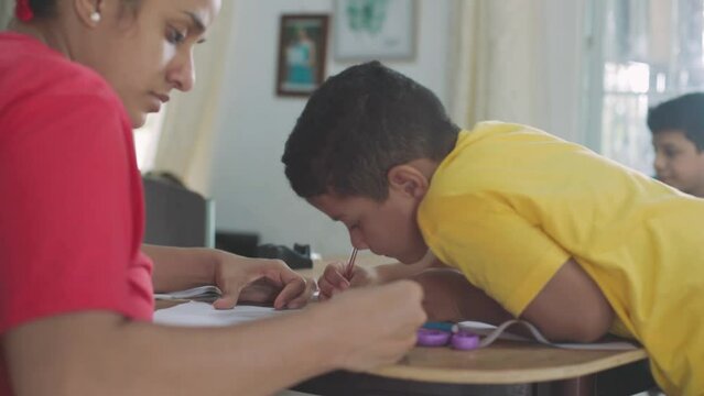 Latina mom teaching her son to paint with colored pencils