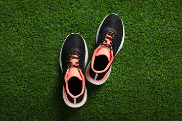 Pair of stylish sport shoes on green grass, flat lay
