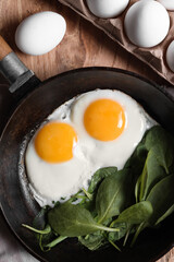 Delicious fried egg with spinach served on wooden table, flat lay