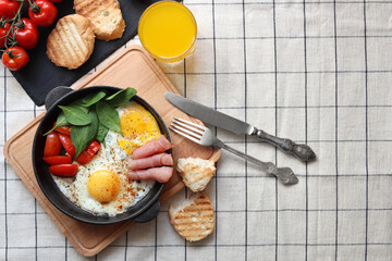 Delicious fried eggs with spinach, tomatoes and ham served on table, flat lay