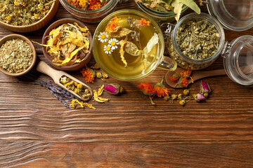Freshly brewed tea and dried herbs on wooden table, flat lay. Space for text