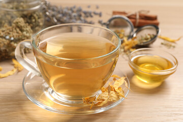 Freshly brewed tea and dried herbs on wooden table, closeup
