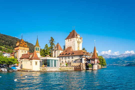 Blick auf Schloss Oberhofen vom Steg aus, mit Eiger M&ouml;nch und Jungfrau im Hintergrund und dem Thuner See, Schweiz 