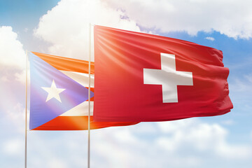 Sunny blue sky and flags of switzerland and puerto rico