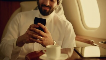 Smiling man texting message in airplane. Closeup hands holding smartphone in jet - Powered by Adobe