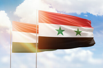 Sunny blue sky and flags of syria and hungary