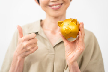 ブタの貯金箱を持ってサムズアップをするミドル女性