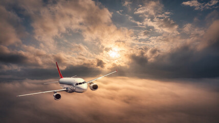 Airplane is flying above the clouds at beautiful sunset in summer. Landscape with passenger airplane, orange sky. Aircraft is taking off. Business travel. Commercial plane. Aerial view. Transport 