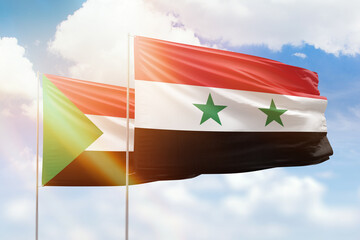 Sunny blue sky and flags of syria and sudan