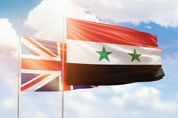 Sunny blue sky and flags of syria and united kingdom