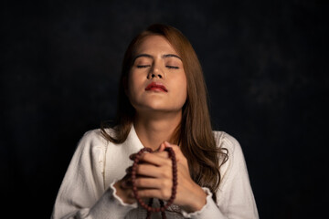 Woman sitting and praying for blessings from god in a room with black background
