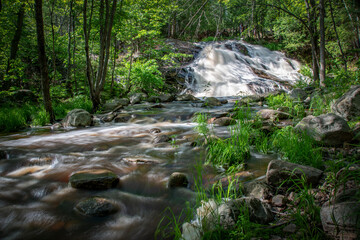 The blurred water of Duchesnay Falls flows down a river through a forest in North Bay, Ontario...