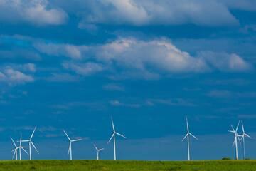 Windmills in a green field against a blue sky.Wind generator in green grass.renewable energy.Alternative energy sources.Environmentally natural energy source.
